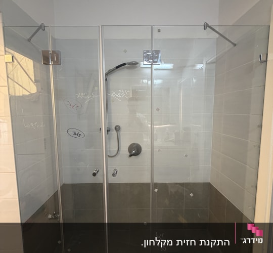 מקלחון זכוכית בחדר אמבטיה עם אריחים אפורים